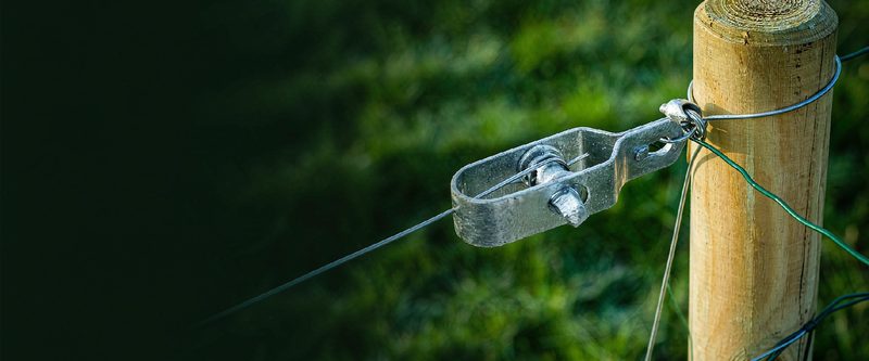 Galvanized wire strainer tensioning fence wire on a wooden post