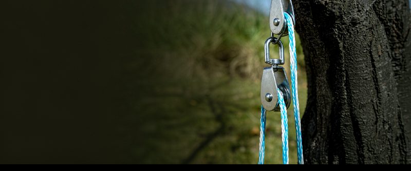Small steel pulley block with braided rope hanging on a wire