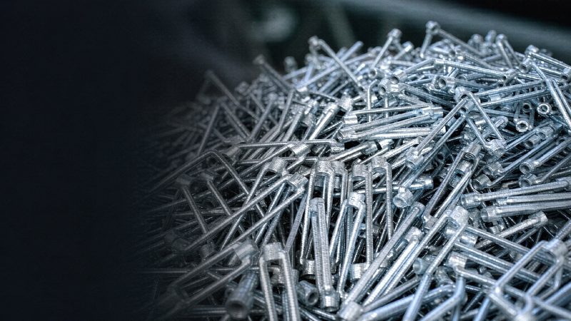 Pile of freshly galvanized steel pins in a production crate